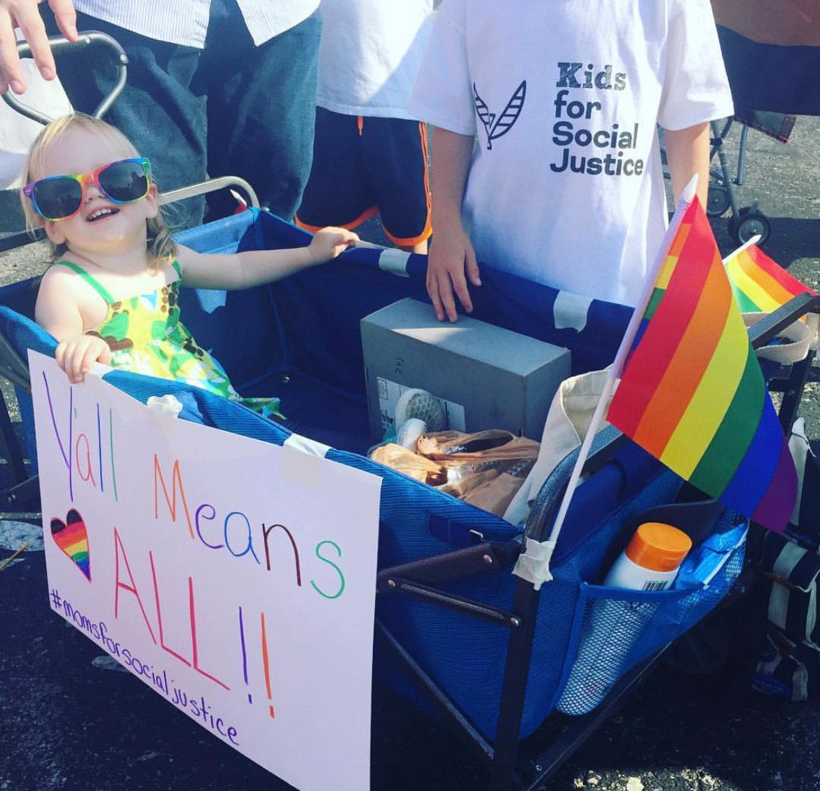 Kids for Social Justice with Pride flag and sign reading "Y'all means ALL!!"