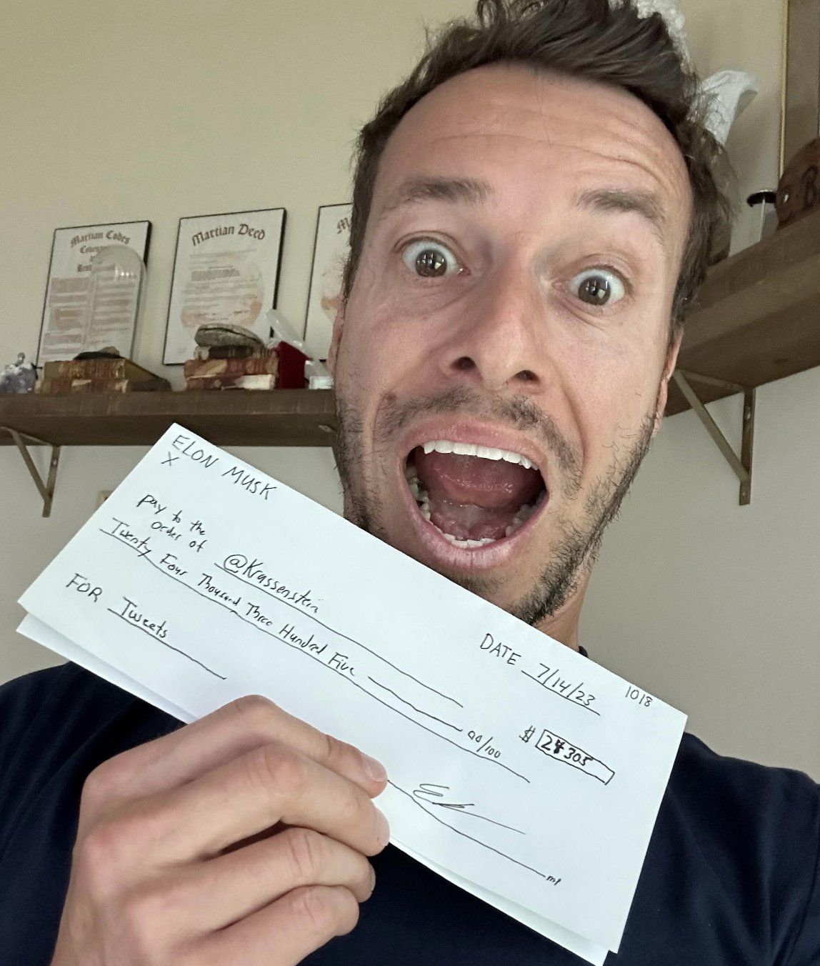 Brian Krassenstein poses with $24,305 "check" from Elon Musk